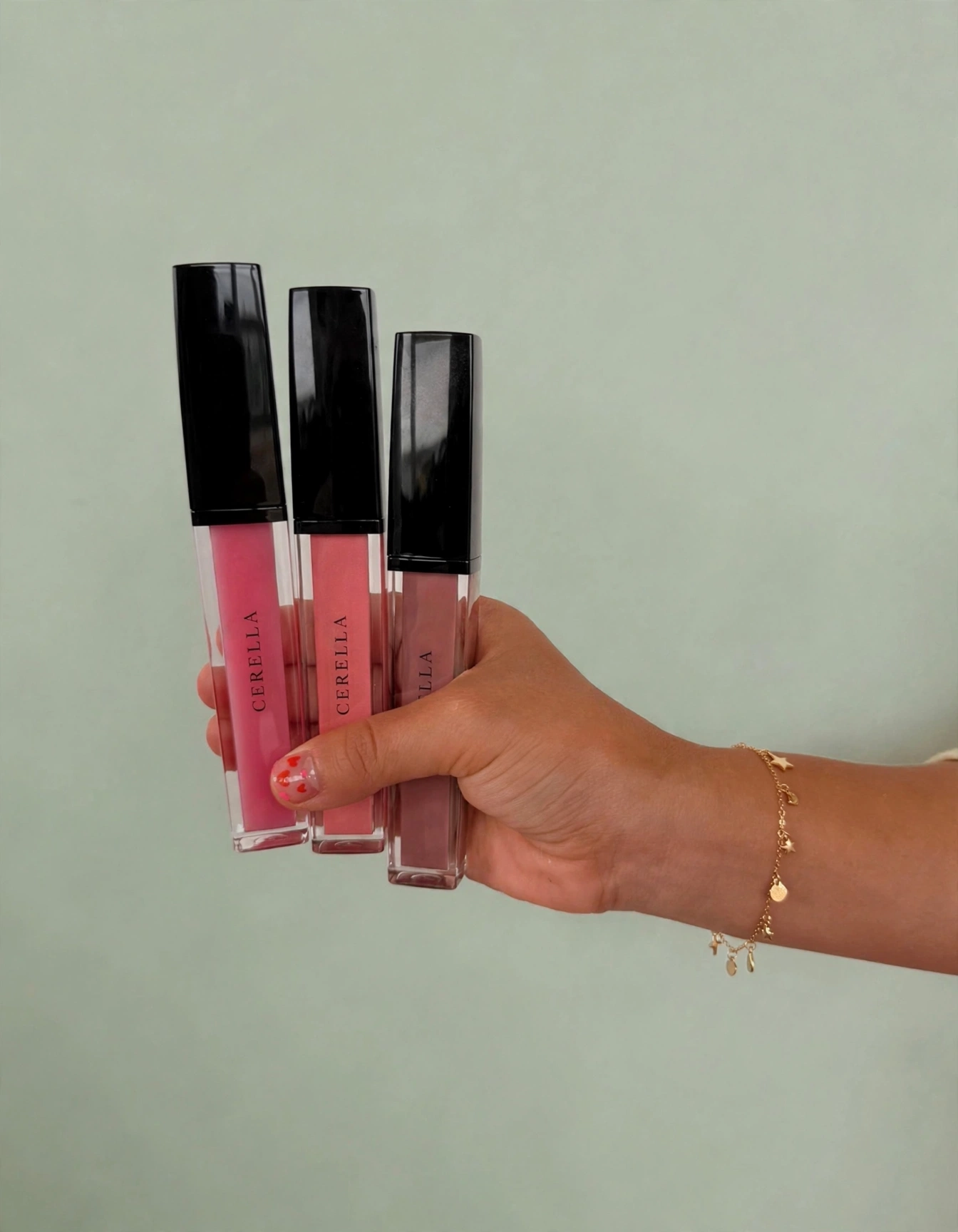 Cerella liquid lip gloss tubes held against a sage background